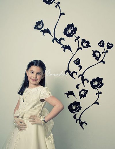 niña con vestido de comunión frente a pared con vinilo de flores