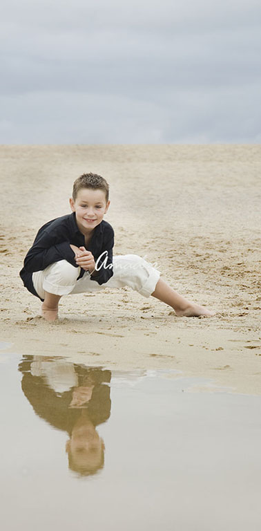 Neno en agachado posando na praia.