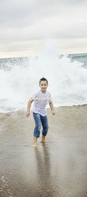 niño en la orilla con las olas de fondo
