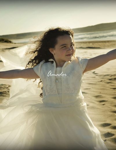 niña con vestido de comunión en la arena