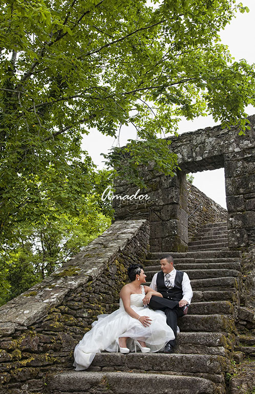 Pareja con trajes de boda en escalinata de piedra