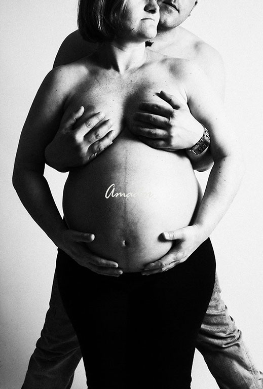 Foto en branco e negro dunha muller embarazada abrazada polo seu compañeiro.